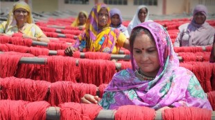 A lady in a headscarf weaves brightly coloured threads