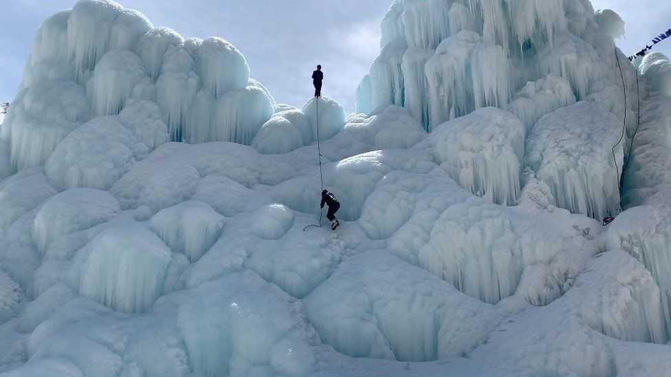 Two people climb a glacier.