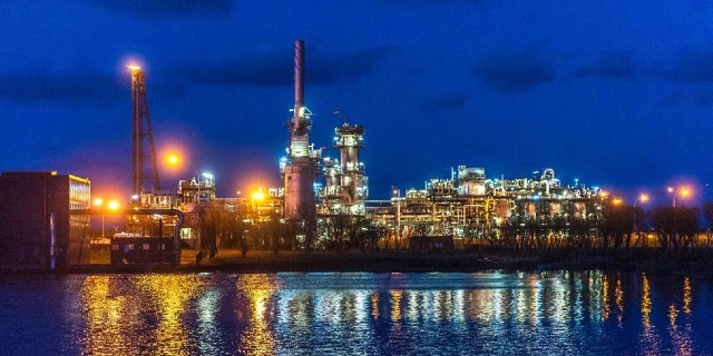 The St Fergus Gas Terminal in Aberdeenshire is seen at night. Two large towers protrude from a collection of industrial buildings, with lights reflected on the water