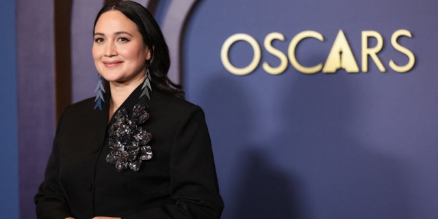 Actress Lily Gladstone smiles in front of the Oscars sign