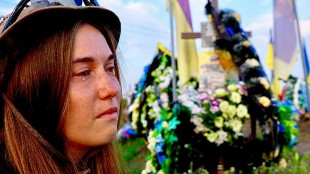 A Ukrainian woman called Oksana cries as she sits next to the grave of her husband, who died in November