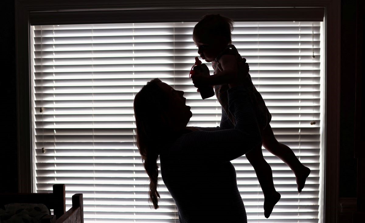 A mother in Birmingham, Alabama, holds her child in front of a window