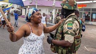 A woman interacts with a soldier as she celebrates with people in support of a putsch in Gabon