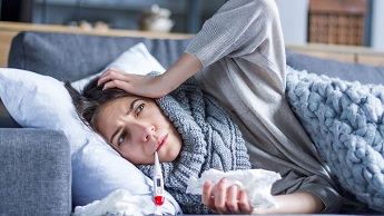 Generic image of woman in bed, using a thermometer