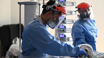 Medical staff work on a patient while wearing protective kit
