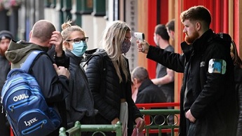 A doorman checks people's temperatures outside a bar