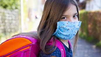 Generic image of a child wearing a face mask and a backpack