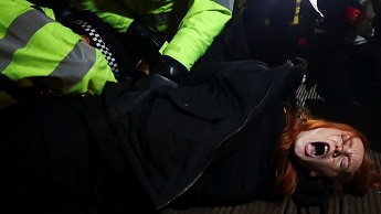 Police detain a woman as people gather at a memorial site in Clapham Common