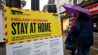 People walk past a government sign in Winchester warning people to stay at home