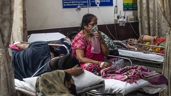 A woman who contracted coronavirus sits connected to oxygen supply inside the emergency ward of a Covid-19 hospital in Delhi on 3 May