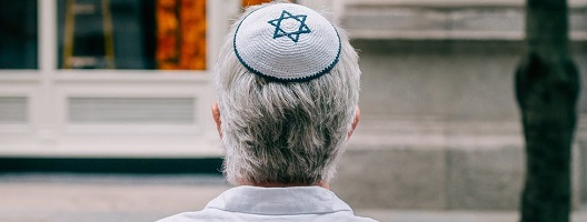 A Jewish man wearing a kippah sits on a bench in London