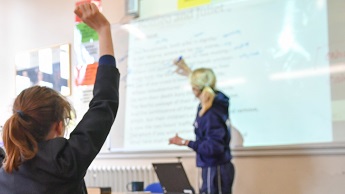 File image showing a pupil raising her hand during a lesson