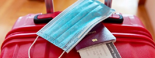 Generic image showing a passport, boarding pass and face mask lying on a suitcase