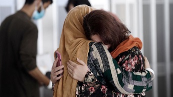 A woman embraces her sister-in-law as she arrives in the US with other Afghan refugees