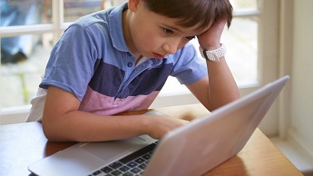 Boy doing home schooling looking at a laptop