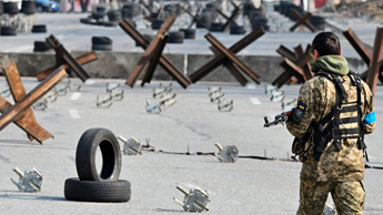 A Ukrainian soldier passes by anti-tank protection elements as he stands guard at a checkpoint in the outskirt of Kyiv on 28 March 2022