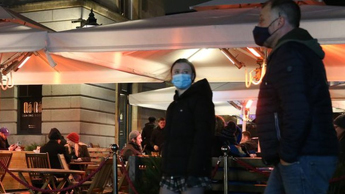 People wearing masks as they walk past a bar