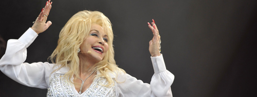 Dolly Parton raising her hands towards her head