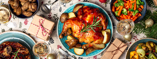 Aerial view of a Christmas dinner table, laden with turkey, vegetables, potatoes, presents and white wine