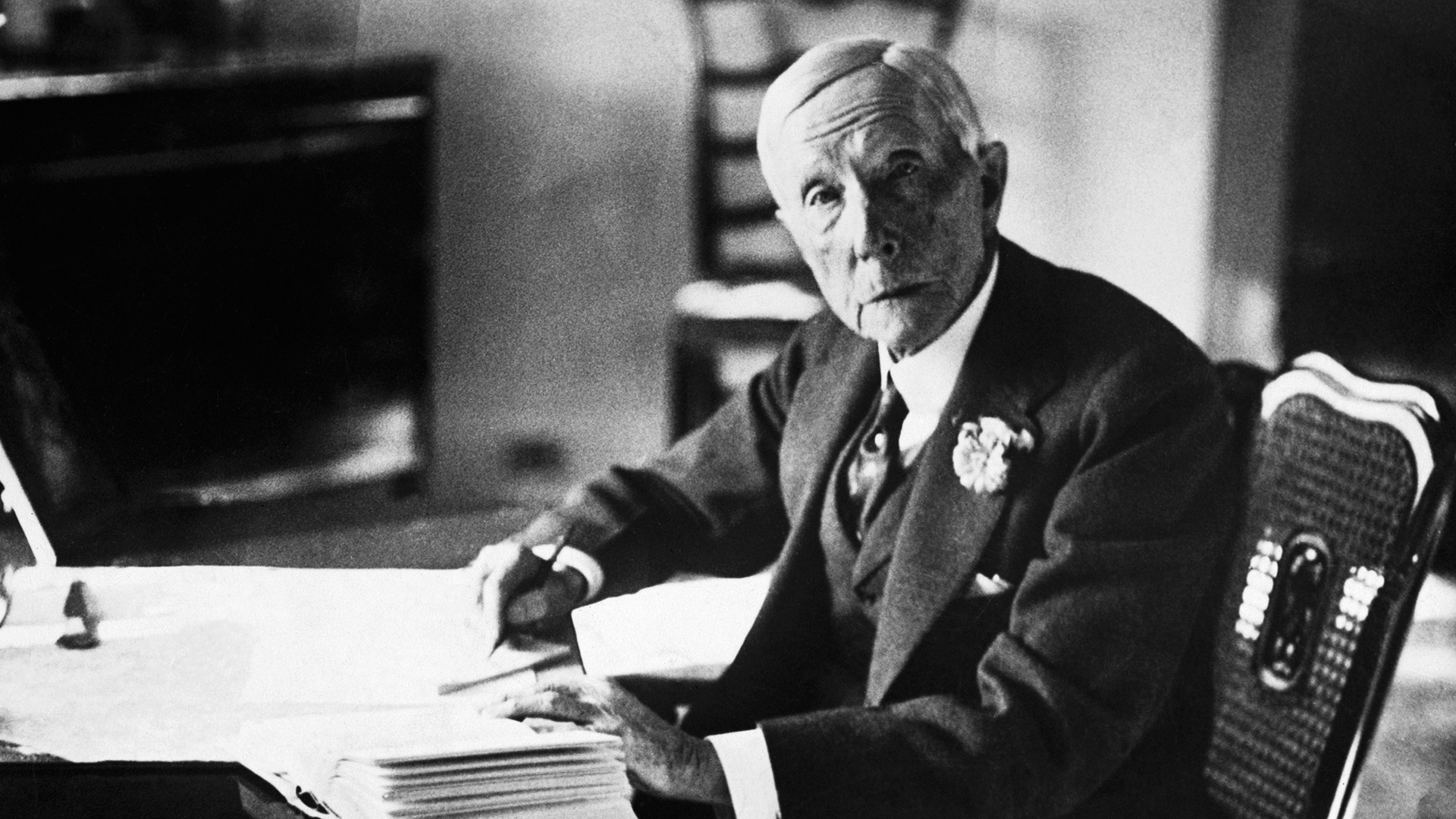 Undated photograph of John D Rockefeller sat at a desk (Credit: Hulton-Deutsch Collection/Corbis via Getty Images)