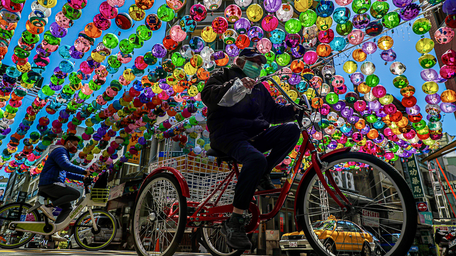 People cycle under colorful lanterns at a tourist attraction area in Changhua, Taiwan (Credit: Ritchie B. Tongo/EPA)